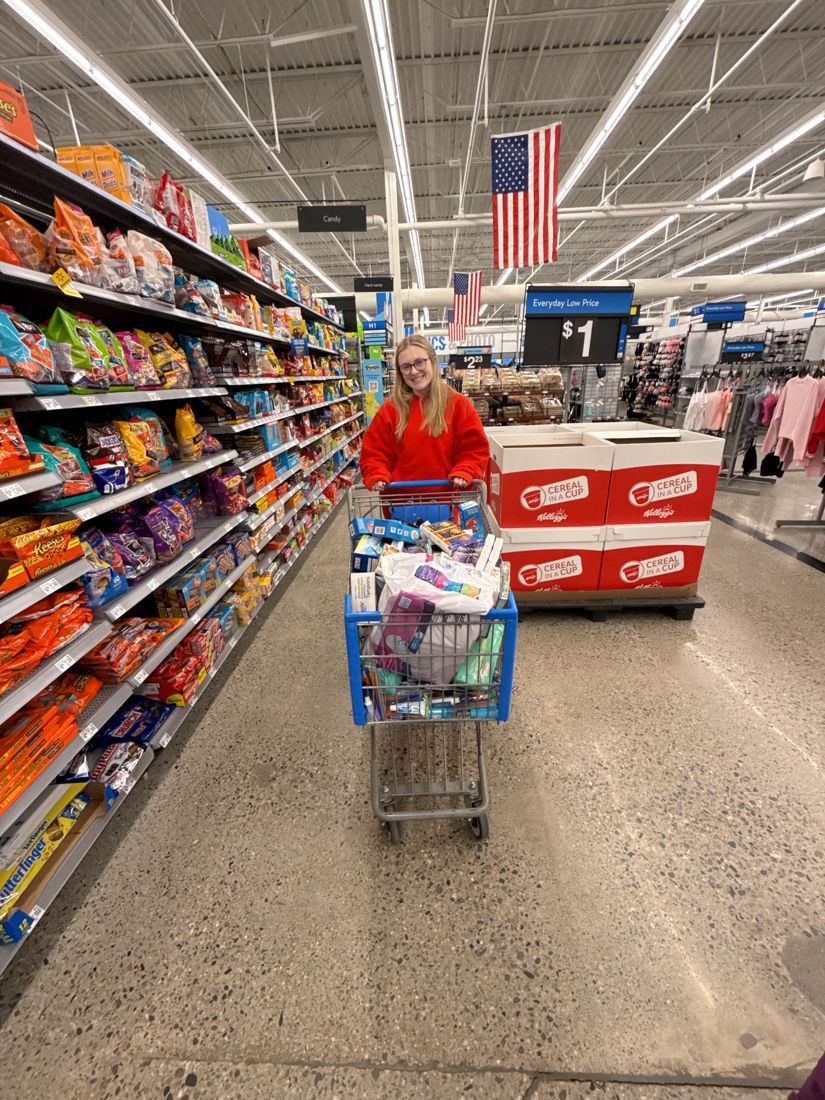 A member pushing a full shopping cart of hygiene products